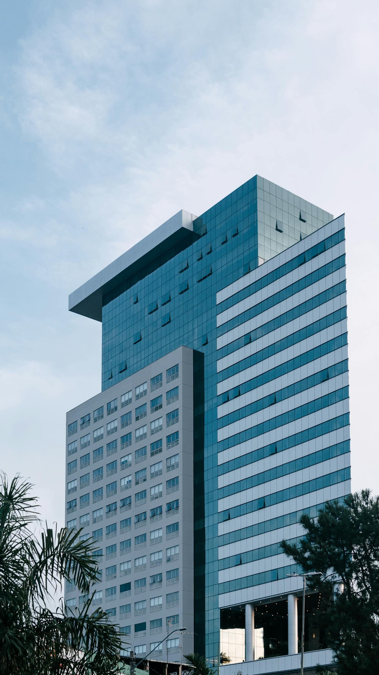 A contemporary glass high-rise office building against a clear sky, showcasing urban architecture.
